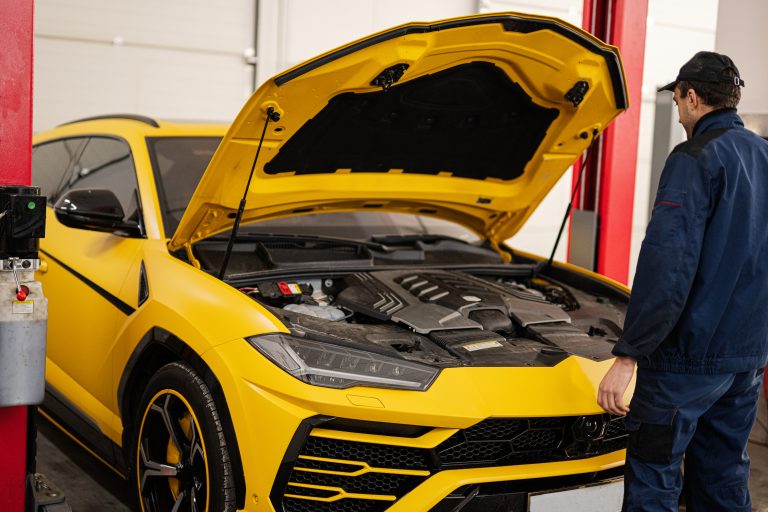 Mechanic open hood of yellow sport car suv